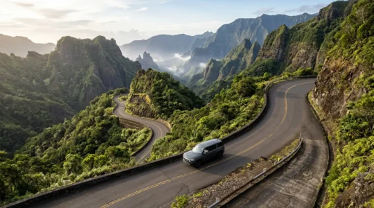 Véhicule sur route de montagne escarpée avec virages serrés et vue sur un cirque tropical en arrière-plan
