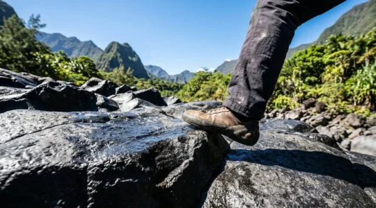 Grimpeur posant précisément son pied sur une paroi de basalte noir caractéristique de la Réunion
