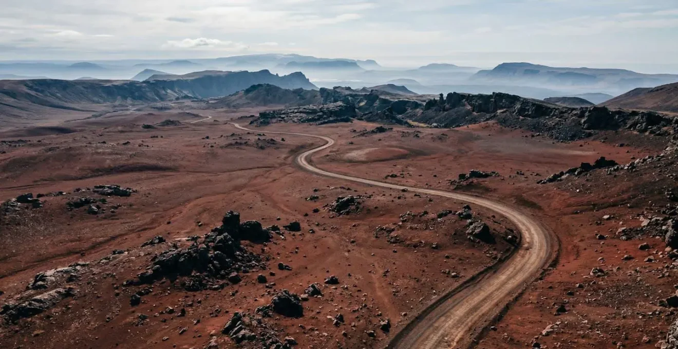 Vue panoramique de la Plaine des Sables avec sa piste sinueuse traversant le paysage lunaire rouge et noir