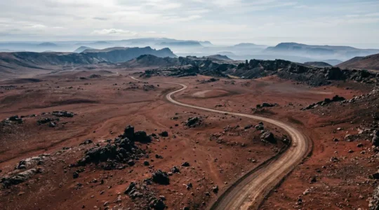 Vue panoramique de la Plaine des Sables avec sa piste sinueuse traversant le paysage lunaire rouge et noir