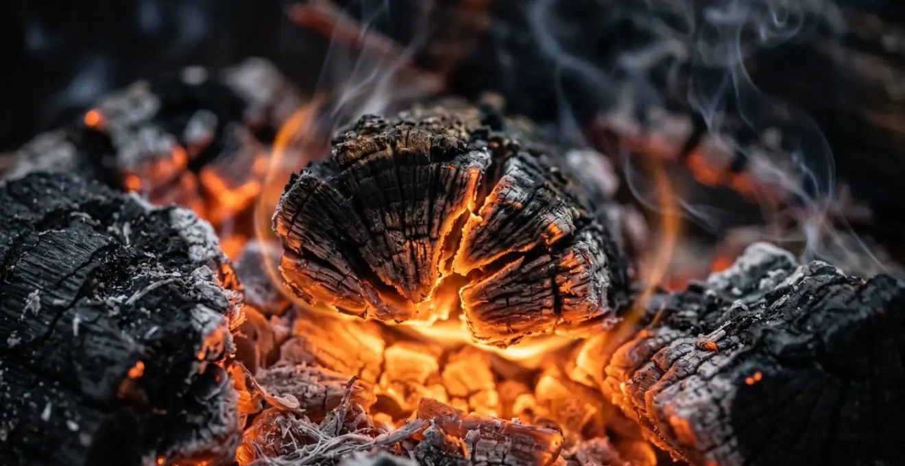 Braises incandescentes de bois de filao avec fumée dorée montant dans l'air