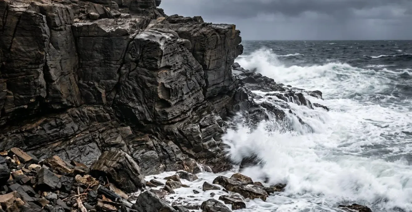 Falaise basaltique érodée par les vagues puissantes lors d'une houle australe à La Réunion, montrant le recul visible du trait de côte