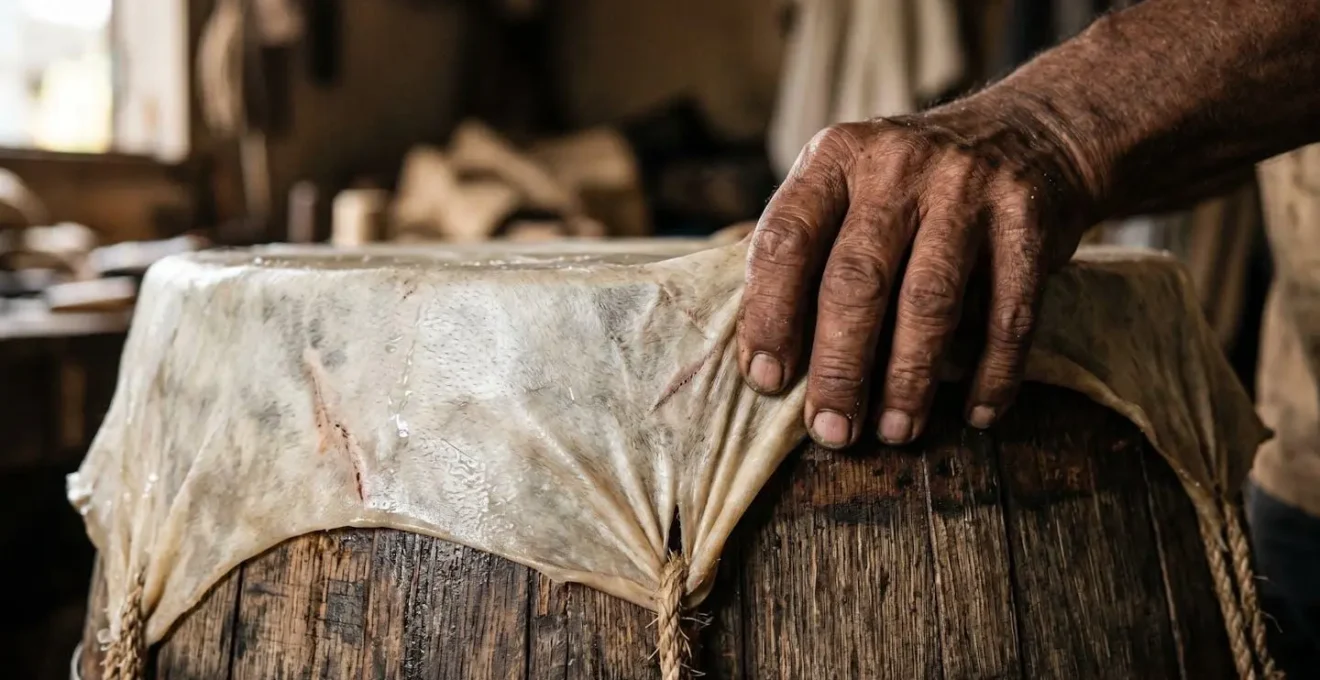 Gros plan sur les mains d'un artisan tendant une peau de bœuf sur un tonneau de rhum recyclé