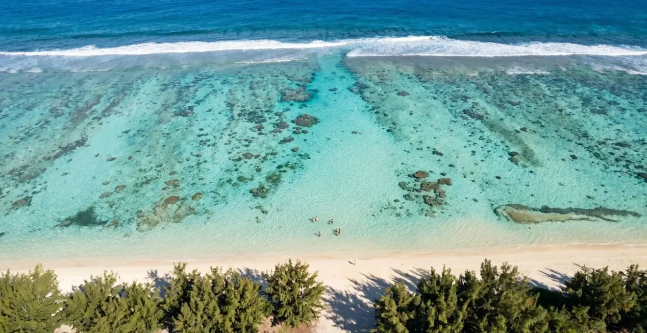 Vue aérienne du lagon de l'Ermitage montrant les eaux turquoise peu profondes, les baigneurs et les zones de coraux visibles