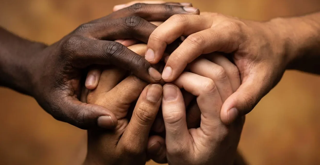 Mains entrelacées de différentes couleurs symbolisant la cohésion sociale malgré les tensions